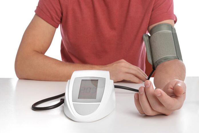 Man checking blood pressure with sphygmomanometer at table again