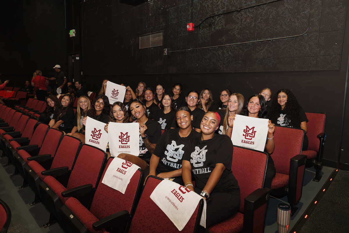 Mt. San Jacinto College Welcomes More Than 400 Student-Athletes Back for the 2026-2027 Academic Year A group of young athletes in black shirts and red seats hold up white signs with "EAGLES" branding, posing together in a theater.